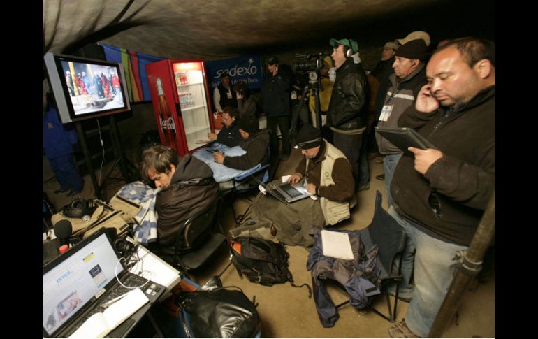 Periodistas observan hoy la transmisión en vivo de los preparativos del rescate de los mineros. AP  /