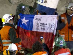 El minero José Ojeda, de 46 años, despliega una bandera chilena mienstras sale de la cápsula. EFE  /