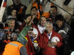 Luis Urzúa (con lentes oscuros), levanta la mano en señal de victoria. A la derecha, el presidente Sebastián Piñera. AFP  /