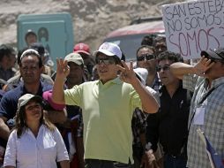 Al fondo un cartel sostenido por personas que protestaban que dice ‘‘San Esteban, no somos 33 los mineros, somos 300’’. EFE  /