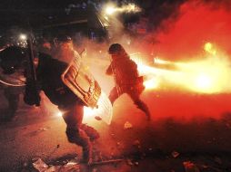 Agentes de la Policía italiana Antidisturbios escapan de los petardos y de los cócteles Molotov arrojados por manifestantes. EFE  /