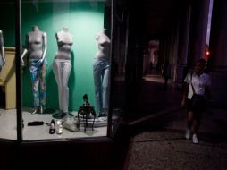 Una mujer camina afuera de una tienda de ropa en Cuba. AP  /