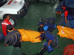 Rescatistas junto algunos cádaveres de habitantes que perdieron la vida durante el tsunami. AFP  /