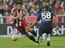 Mario Gómez (izq.) trata de avanzar ante la marca de un elemento dle Friburgo. AP  /