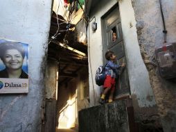 Un niño llega a su casa en el barrio de Doña Martha, en Río de Janeiro. A la izquierda un poster con la imagen de Dilma Rousseff. AP  /