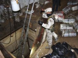 Un soldado mexicano permanece a un lado de la entrada del narcotúnel y observa los paquetes de droga. REUTERS  /