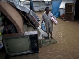 Una mujer cuida si pertenencias en un acalle inundada de Haití. AP  /