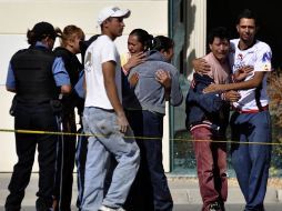 Familiares de los oficiales de Policía reaccionan ante la escena del crimen, en Ciudad Juárez. AP  /