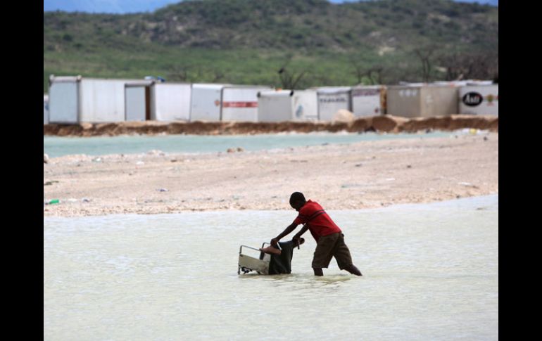 Un niño empuja una silla de ruedas por el inundado Malpase, en Haití. EFE  /