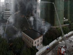 Bomberos combaten el fuego en el edificio en proceso de remodelación, en el Centro de Shangai. EFE  /
