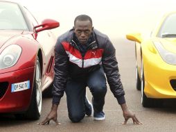 Bolt posa junto a un Ferrari 458 Italia (d) y un 599 Fiorano GTB (i). EFE  /
