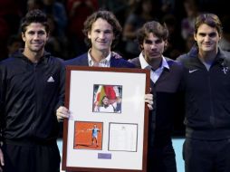 El tenista español Carlos Moyá sostiene un cuadro con imágenes de su carrera durante el homenaje que recibió en Londres. AP  /
