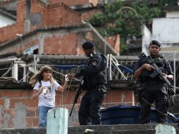 Una niña ofrece agua a miembros del Batallón de Operaciones Especiales en la favela Morro dos Macacos. EFE  /
