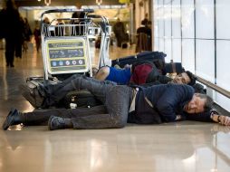 Viajeros descansan en el Aeropuerto de Madrid-Barajas, en espera de la salida de sus vuelos. EFE  /