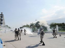 Policías lanzan gases lacrimógenos para dispersar a los inconformes. AFP  /