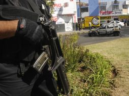 Agentes federales resguardan la zona donde un auto fue incendidado para bloquear la calle. NOTIMEX  /