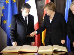 El presidente francés, Nicolas Sarkozy y la canciller alemana, Angela Merkel, firman el libro de visitas de Friburgo. AP  /