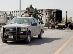 Agentes de la Marina pasan por una carretera donde sicarios bloquearon el paso con varios vehículos. AFP  /