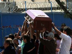 Familiares de uno de los reclusos que murió en una cárcel pasan con el ataúd frente al penal de San Miguel en Santiago de Chile. EFE  /