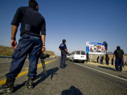 Personal de la PGR coloca en Michoacán un cartel con imágenes de integrantes de La Familia buscados por las autoridades. AFP  /