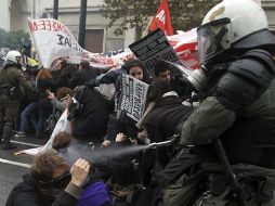 Varios policías antimotines se enfrentan a un grupo de manifestantes frente a las puertas del Parlamento en Atenas. EFE  /
