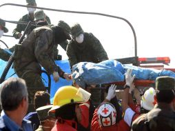 Paramédicos entregan a militares el cadáver de una de las víctimas mortales de la explosión de un ducto en Puebla. EFE  /