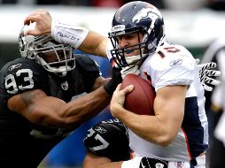 Tebow, mariscal debutante de los Broncos, es alcanzadopor dos defensivos de Oakland. AP  /
