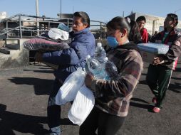 Residentes de San Martín Texmelucan cargan cobijas y víveres proporcionados por el Gobierno federal. REUTERS  /