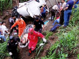 Policías  y bomberos llevan el  cuerpo de un pasajero. AP  /
