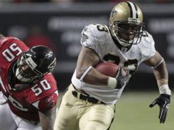 El jugador de los Santos de Nueva Orleans, Pierre Thomas corre avadiendo el ataque de Curtis Lofton de Atlanta. AP  /