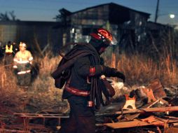 Un bombero camina entre los escombro del almacén que se incendió. AP  /