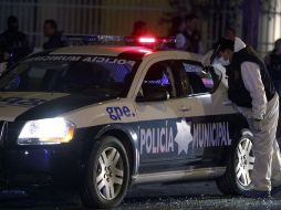 Peritos forenses reúnen evidencias en la patrulla donde fue asesinada a tiros una mujer policía mientras circulaba en Guadalupe. EFE  /