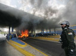 Policías resguardan una caseta en llamas de la autopista que une a las ciudades bolivianas de El Alto y La Paz. EFE  /