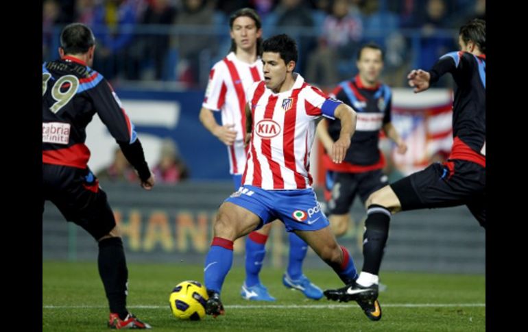 El delantero argentino del Atlético de Madrid, Sergio Kun Agüero (c), controla el balón entre los defensas del Racing de Santander. EFE  /