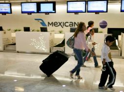 Una familia pasa por uno de los mostradores vacíos de Mexicana, en el aeropuerto capitalino. ARCHIVO  /