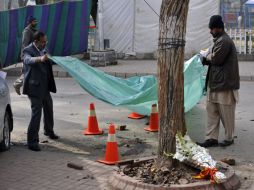 Investigadores paquistaníes cubren la mancha de sangre que queda en el lugar del asesinato del gobernador de Punjab. AFP  /
