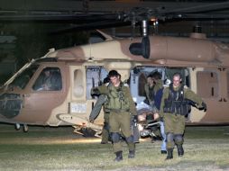 Soldados llevan a sus compañeros heridos a un helicoptéro para que los traslade a un hospital. AP  /