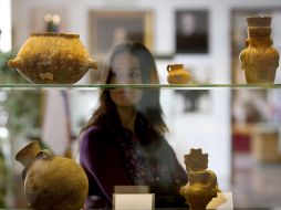 Una mujer observa algunas de las piezas que componen la exposición Recuerdos de cien años de historia. EFE  /