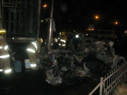 Bomberos limpian la zona en la que fueran incendiados en Carretera a Chapala tres vehículos, la noche del sábado. M. PATIÑO  /
