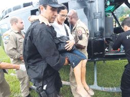 Un policía auxilia a una mujer de edad avanzada a bajar del helicóptero, en Río de Janeiro. NTX  /