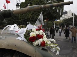 Manifestantes colocaron un ramo de flores sobre uno de los tanques que vigilan el centro de Túnez. AP  /