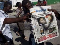 miran la portada de un diario con las fotografías de los ex presidentes Jean-Claude Duvalier (izq.) y Jean Bertrand Aristide (der.). AP  /