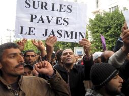 Tunecinos en las calles. Un cartón con la leyenda en francés Encima de las piedras, hay un jazmín. EFE  /