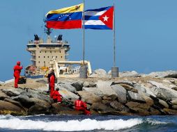 Trabajadores al lado de las banderas de Venezuela y Cuba. REUTERS  /