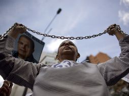 • Una opositora al presidente Hugo Chávez marcha con cadenas en las manos, en Caracas. AP  /