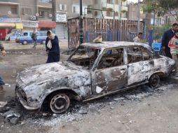 Varias personas caminan junto a un vehículo carbonizado durante las manifestaciones en Egipto. EFE  /