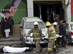 Bomberos del departamento de incendios, policías y paramédicos trasladan a una víctima en una camilla. EFE  /