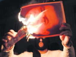 Foto del presidente Hosni Mubarak, arde en manos de un manifestante en El Cairo. Afronta la peor crisis en 30 años de gestión. REUTERS  /