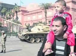 Un hombre carga a un menor frente a vehículos de combate del Ejército, cerca del Museo de El Cairo. EFE  /