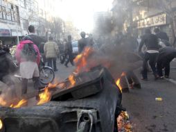 Manifestantes prenden fuego a botes de basura en las calles de Teherán. Policías tratan de repeler las agresiones. EFE  /